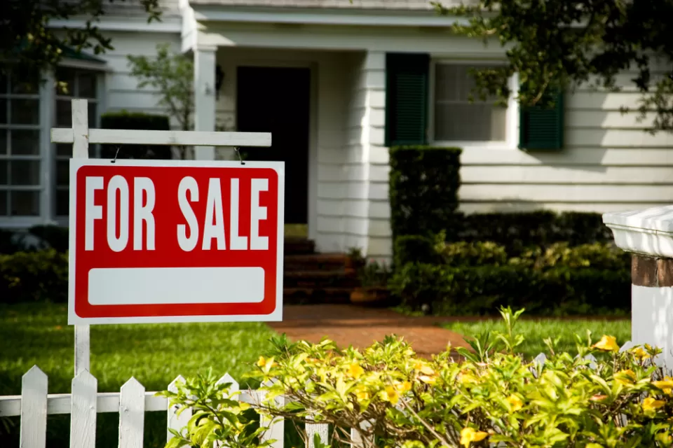White clapboard house with For Sale sign in front yard